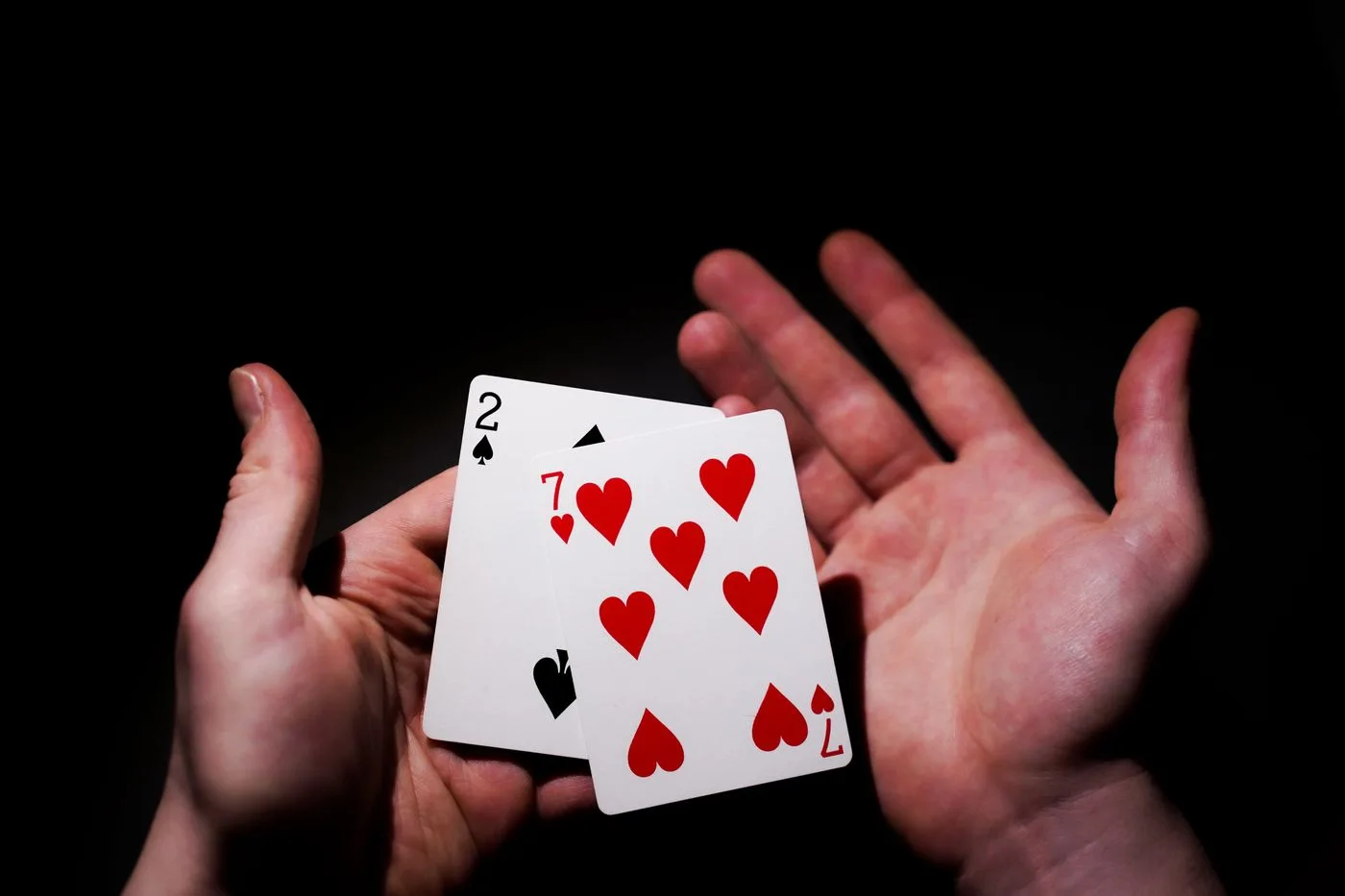 Two playing cards held over a dark tabletop