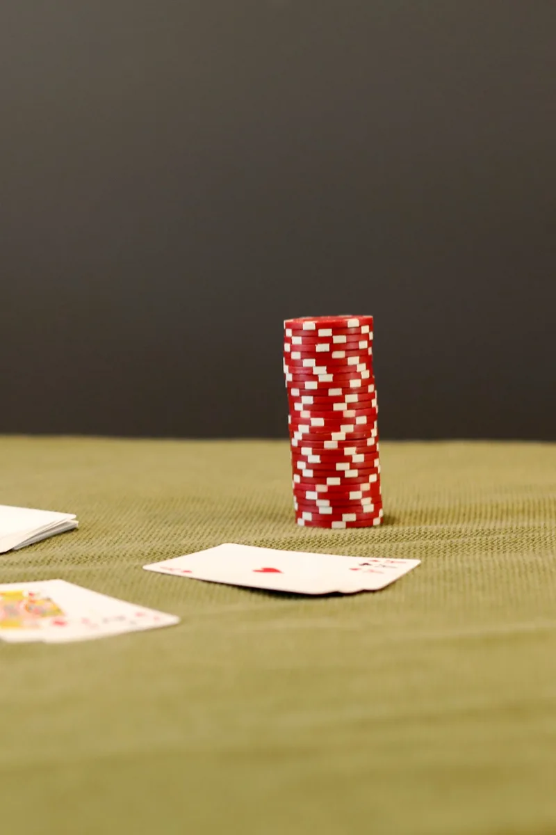 A stack of red chips beside playing cards